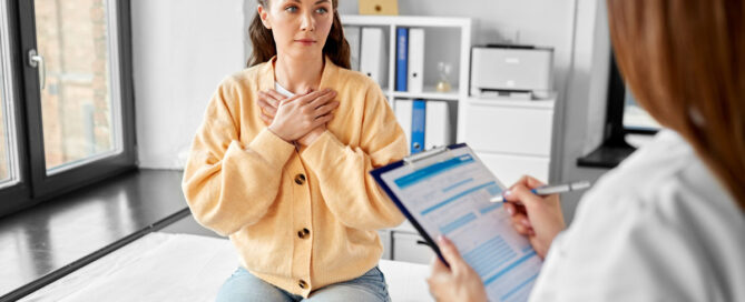 Woman at a doctor's office with hands on chest