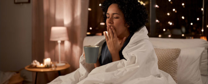 A woman yawning in her bed