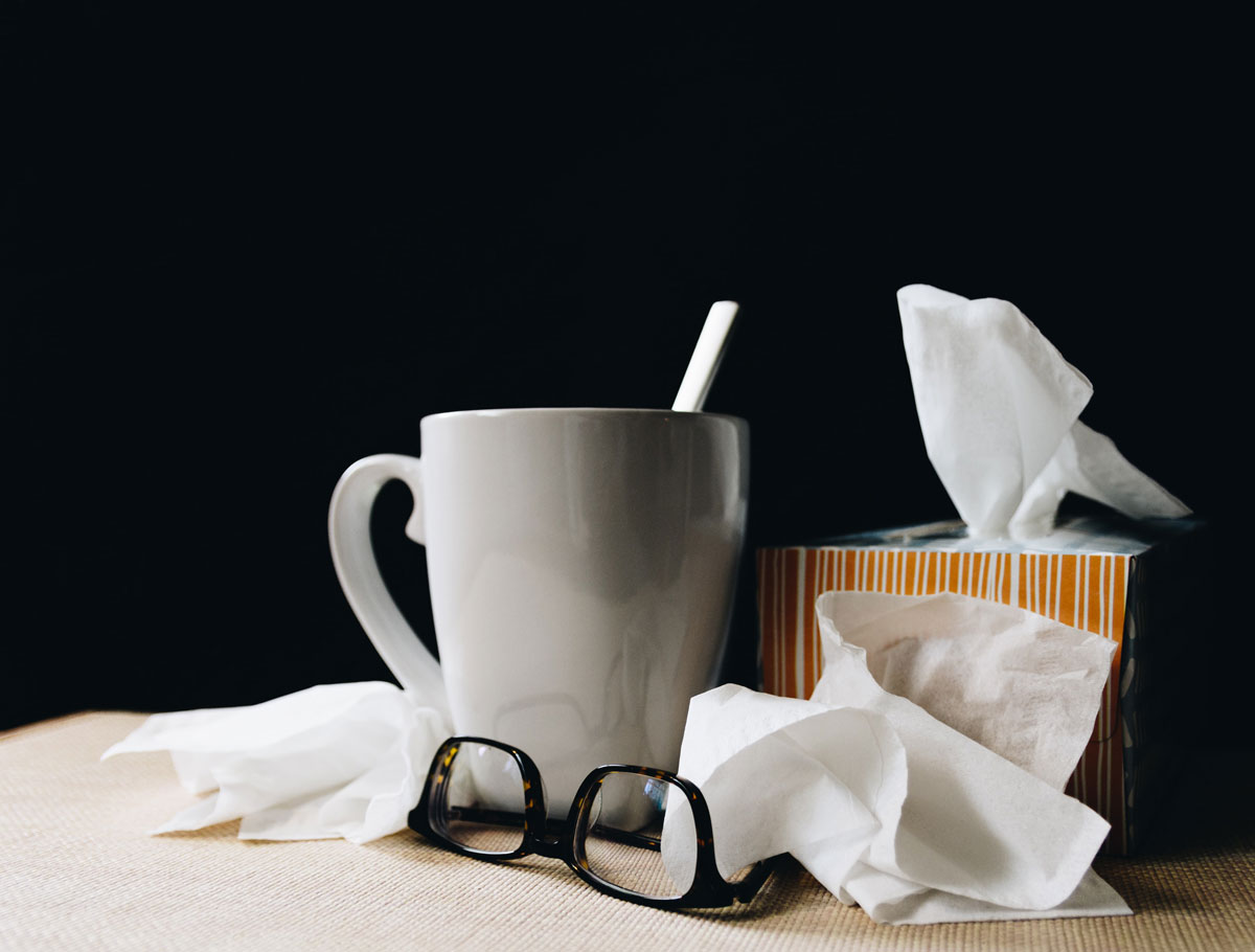 Box of tissues, glasses, and cup of tea on a table