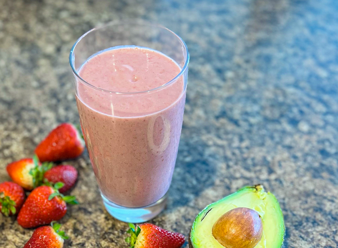 Vegan Strawberry Beauty Smoothie in a glass beside strawberries and avocado