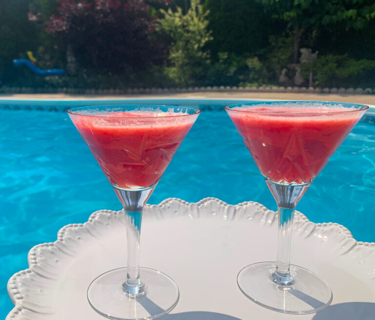 Hot pink Elderberry Burst Mocktail in martini glasses by the pool