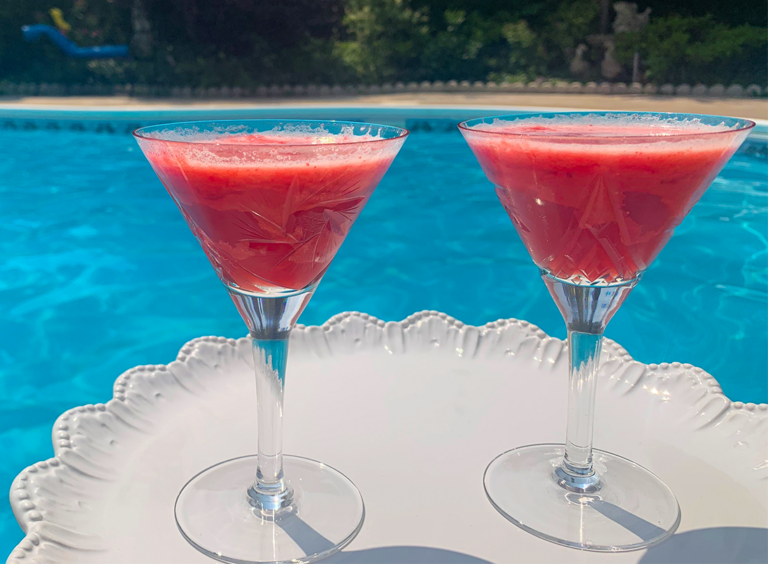 Hot pink Elderberry Burst Mocktail in martini glasses by the pool