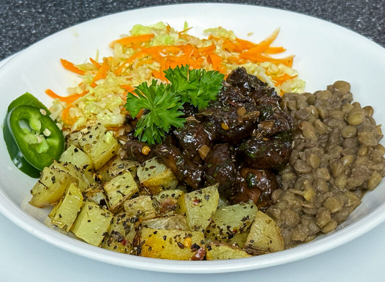 savoury balsamic marinated mushrooms in a white bowl with lentils, roasted potatoes and veggies.