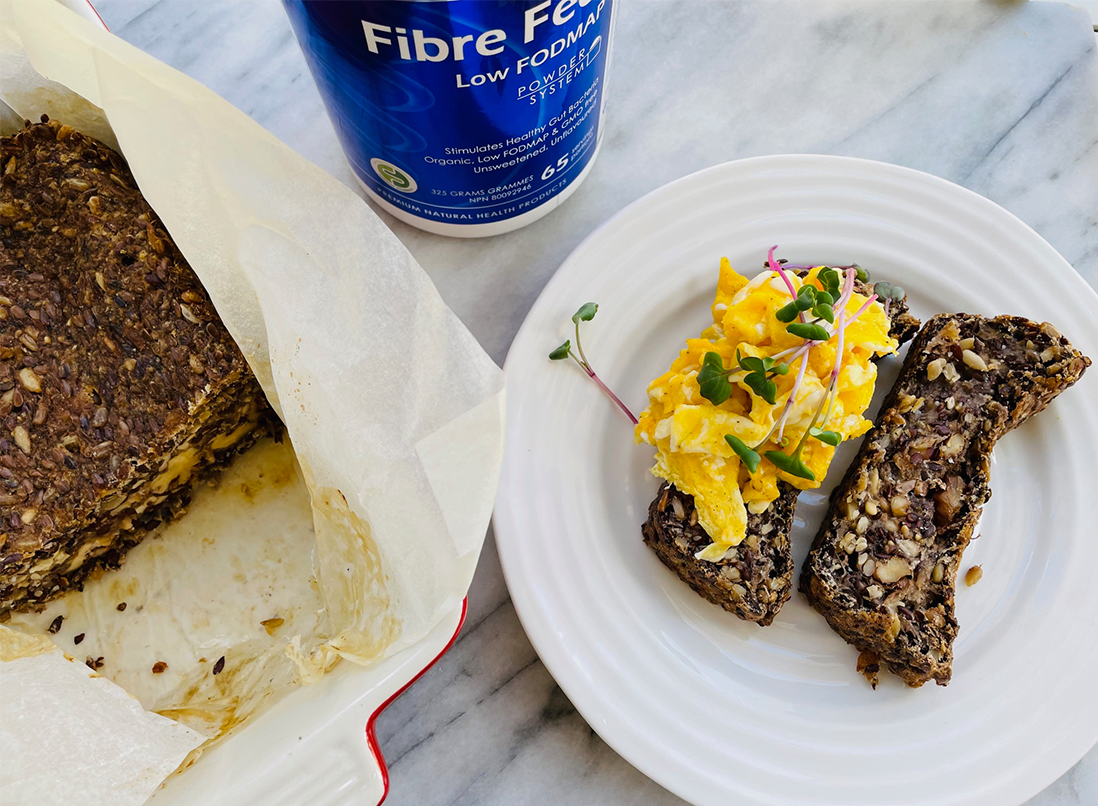 Fibre-ific Bread sliced on a plate with scrambled eggs and fresh sprouts