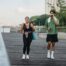 Woman and man in workout clothing walking along a board walk with water bottles in their hands