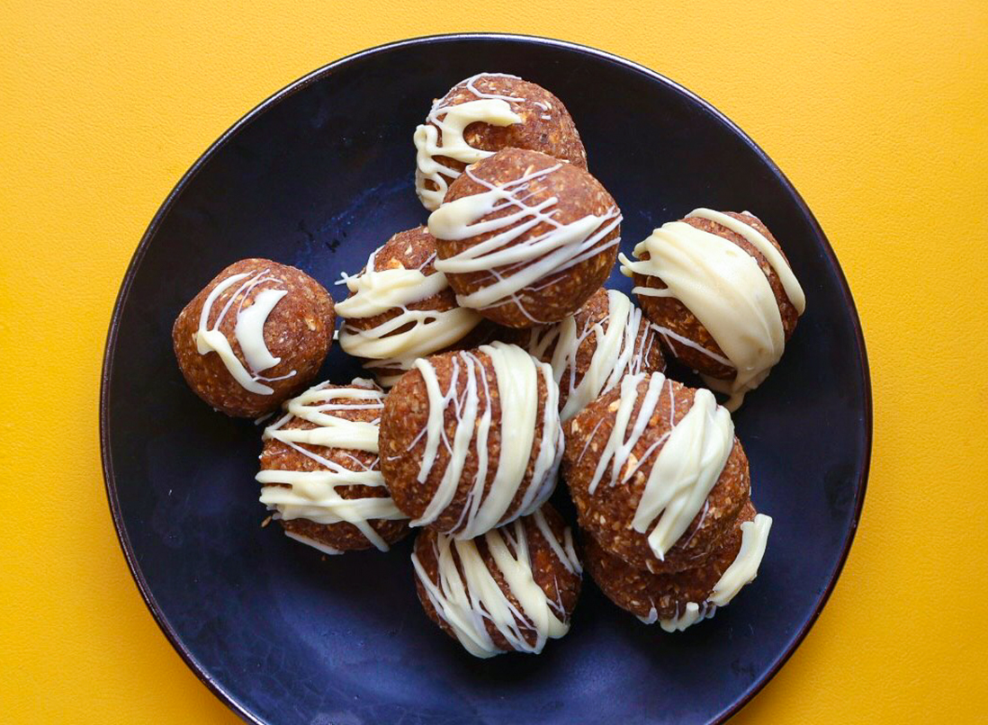 no-bake carrot cake truffles on a blue plate, drizzled in white chocolate.