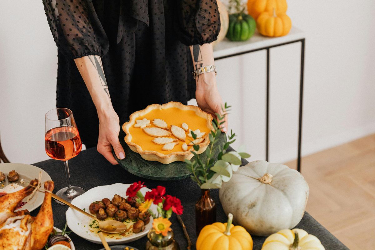 Fall food table display with woman's hand holding a pumpkin pie