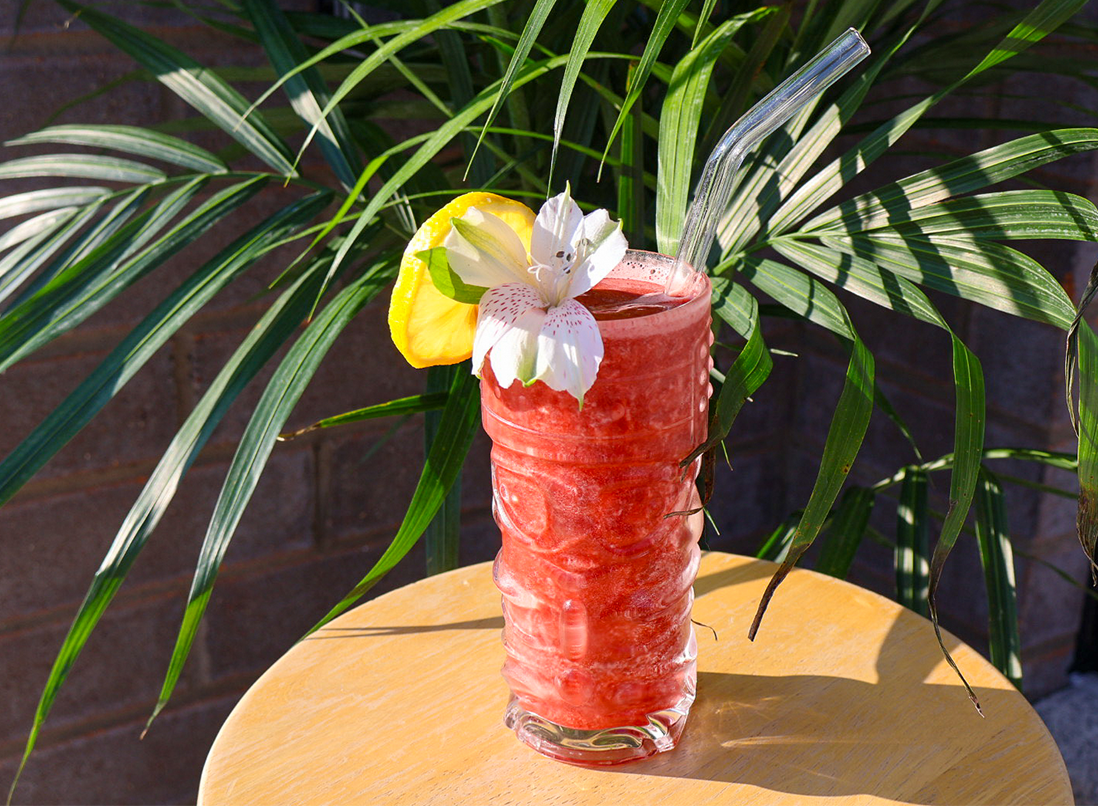 Frozen red slushy Very Cherry Punch in a glass in a tropical setting