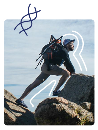 Hiker wearing a helmet and backpack climbs over rocky terrain on a sunny day.