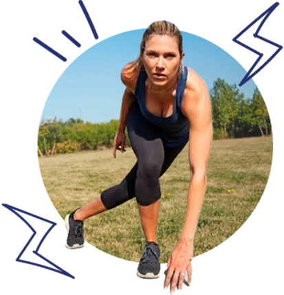 Athlete in a sprint-start position on grass in a park, reaching forward with one hand and one knee on the ground.